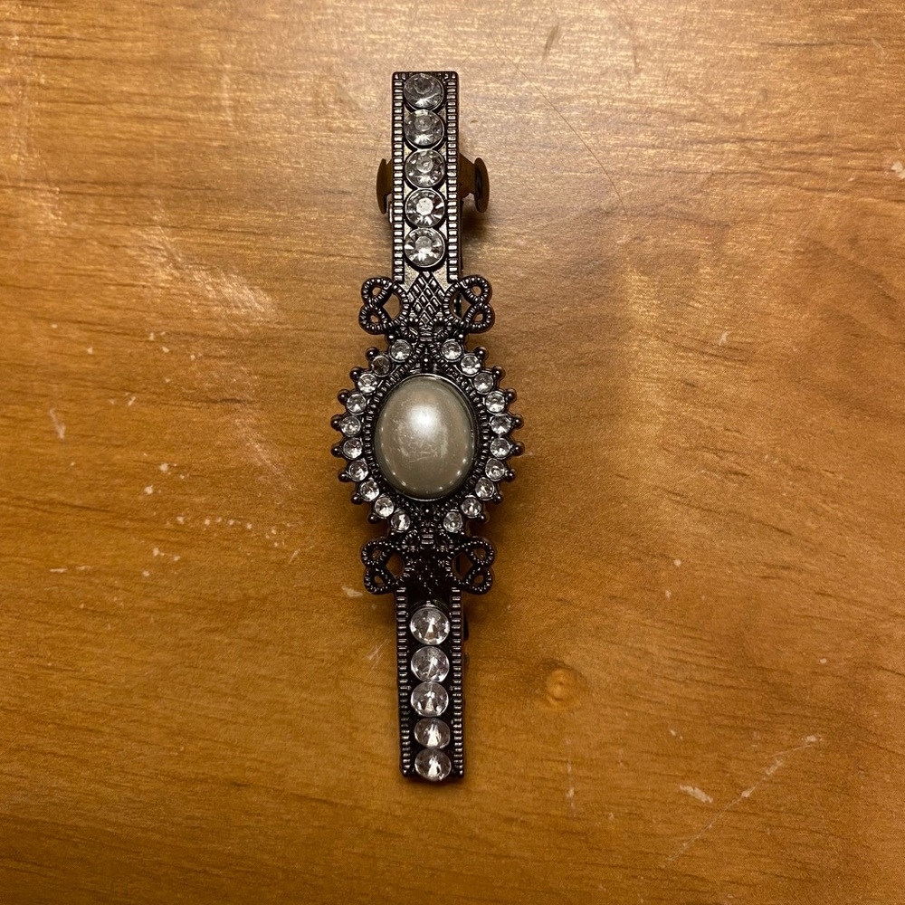 Silver vintage hair clip with shiny crystals and a big pearl in the middle.